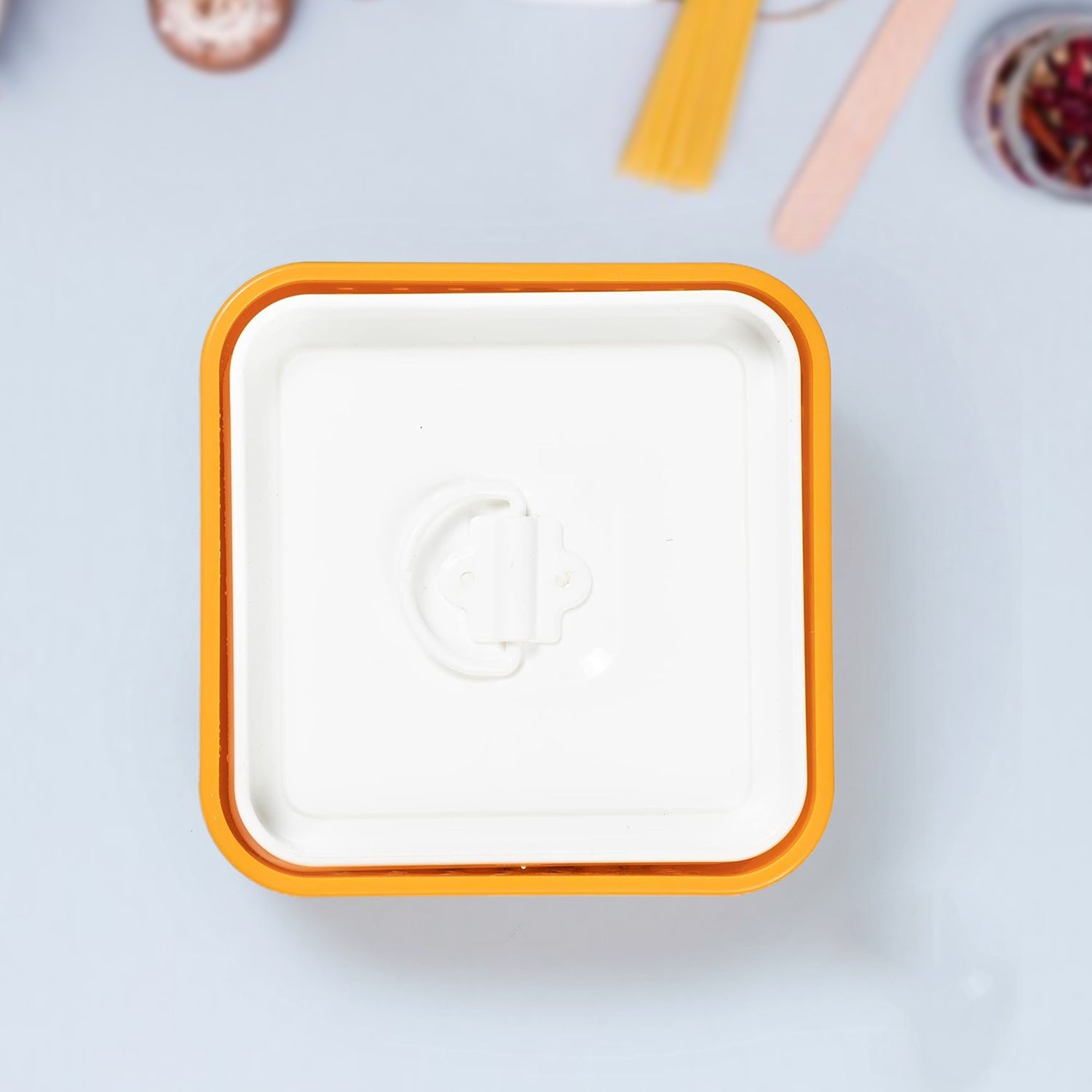 Square white plate with orange rim on a light gray background